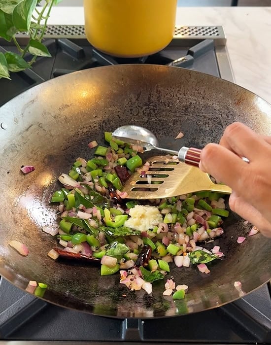 ginger garlic paste being added to a wok