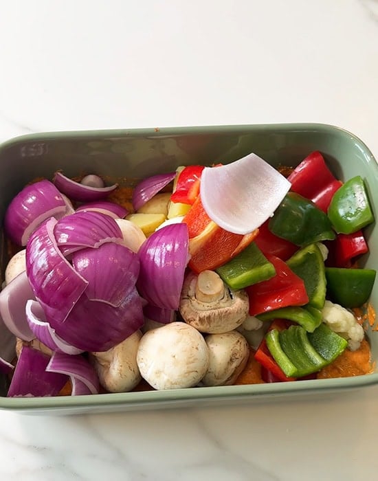 cubed vegetables added to a marinade in a pan