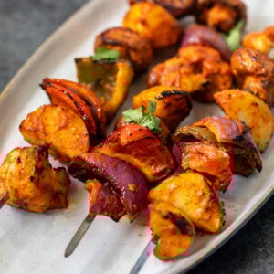 3 veggie skewers arranged on a white oval serving plate