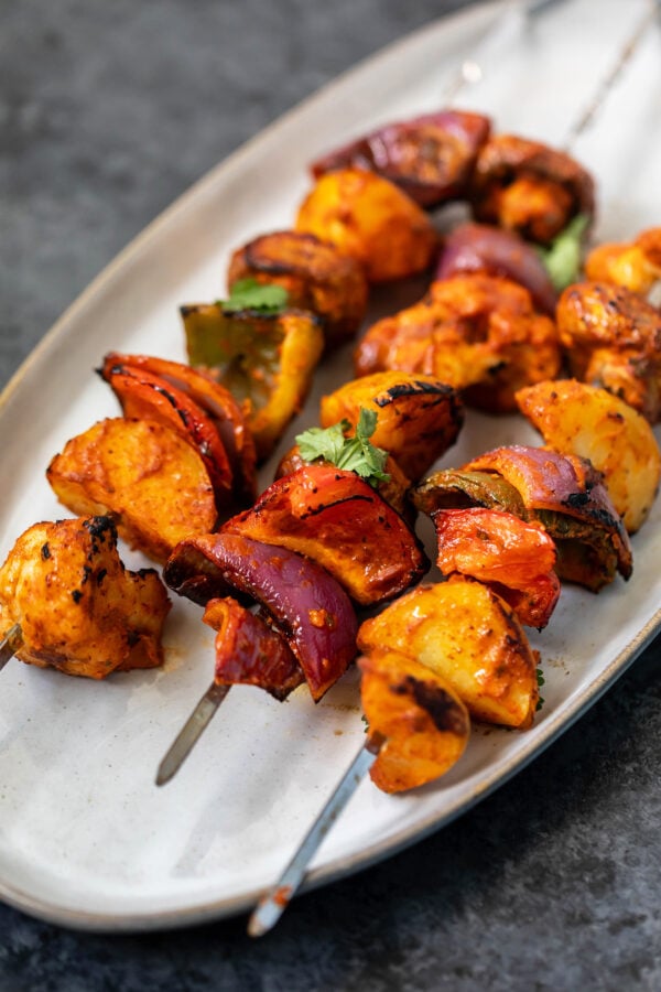 3 veggie skewers arranged on a white oval serving plate