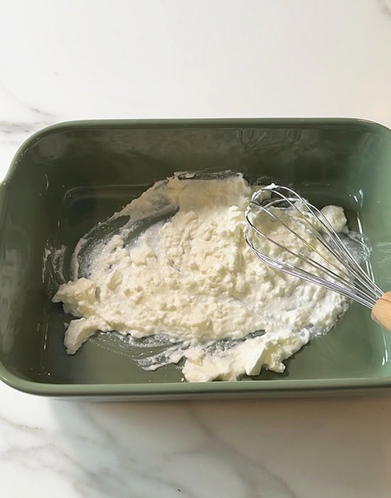 a wire whisk whisking yogurt in a pan