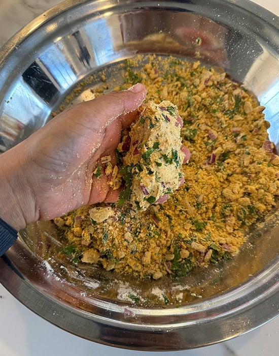 a hand pressing sattu stuffing to show the consistency of the stuffing