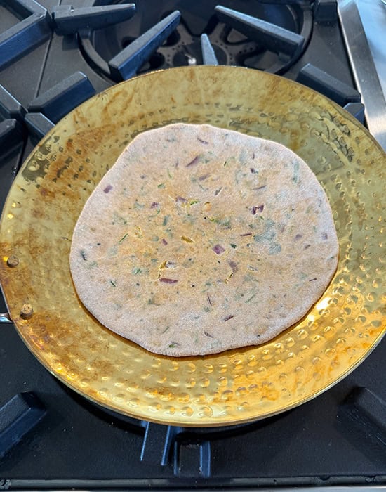 paratha getting cooked on a brass tawa
