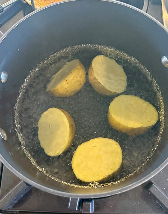 5 cut potatoes with skin boiling in water in a pot