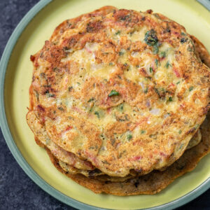 stack of moong dal chillas placed on a yellow color round plate with green rim