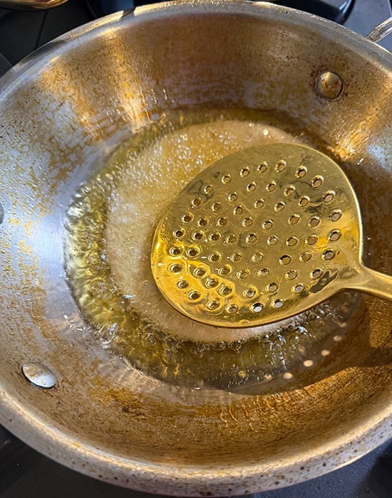 spatula pressing puri in oil to make it fluff