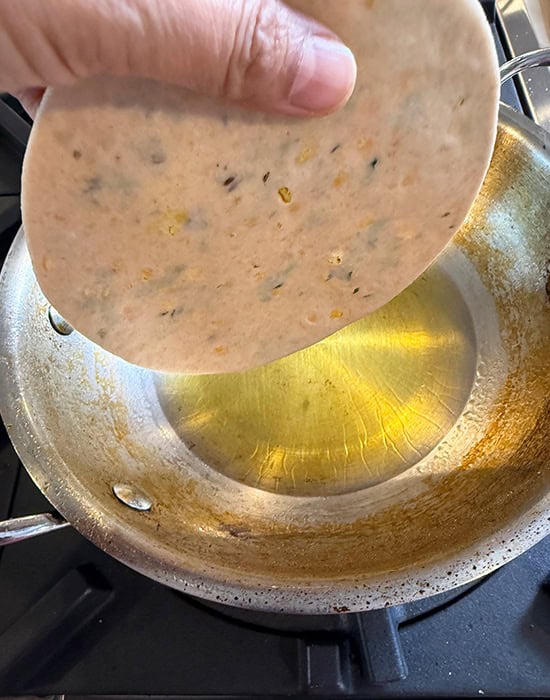 hand dropping puri in hot oil