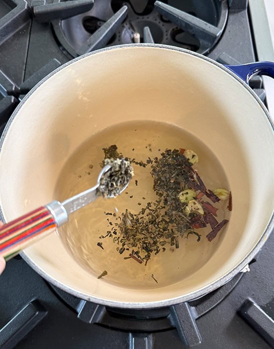 green tea added to a pot with water and spices