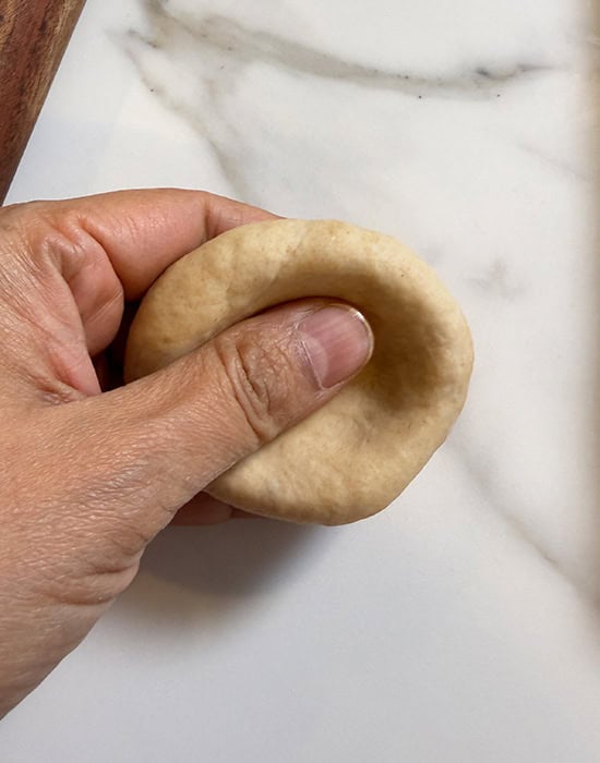 a dough ball being pressed in the center to make an indent