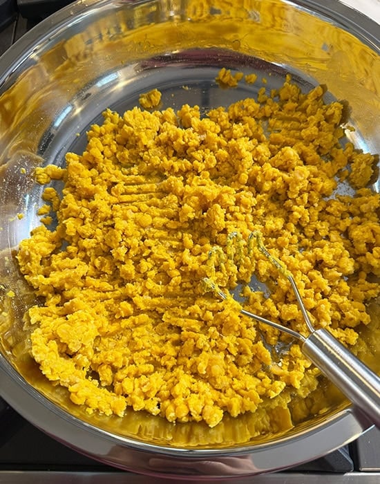 mashing cooked dal using a potato masher