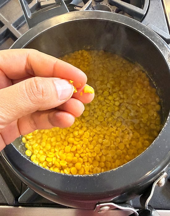 dal being mashed with fingers to check if its done
