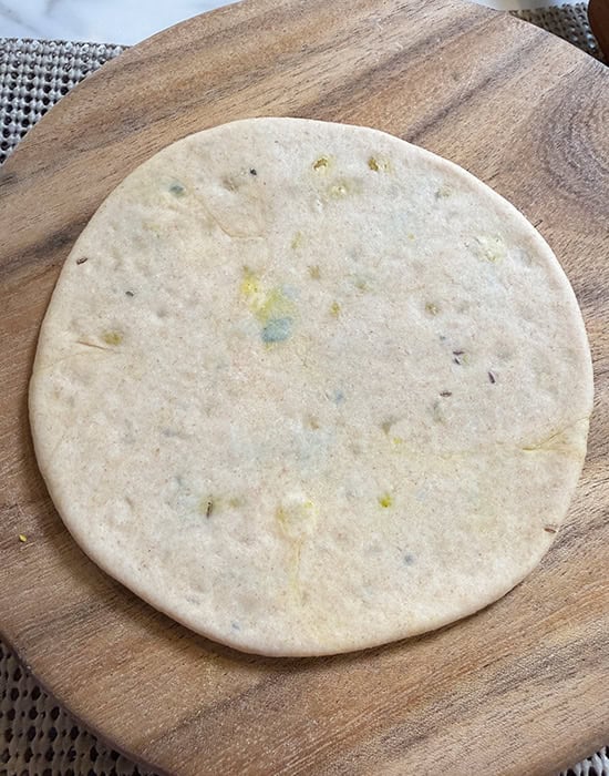 a rolled puri placed on a rolling board