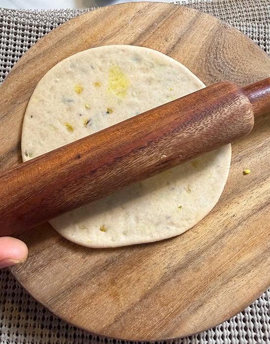 hand rolling a puri with a rolling pin