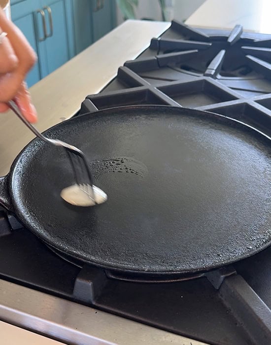 onion being rubbed on a dosa tawa