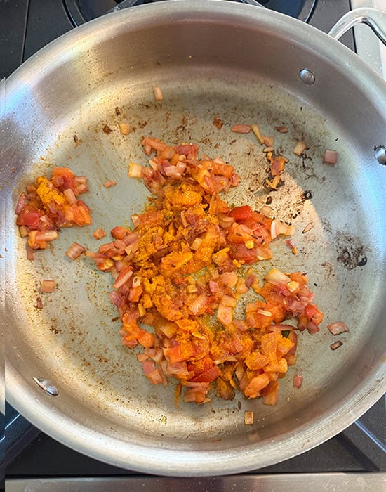cooked onions and tomatoes in a steel pan
