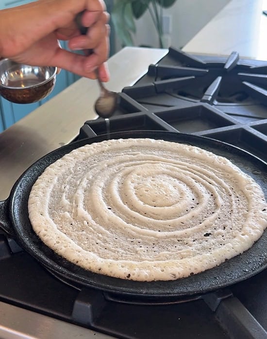 spreading oil on sides of dosa