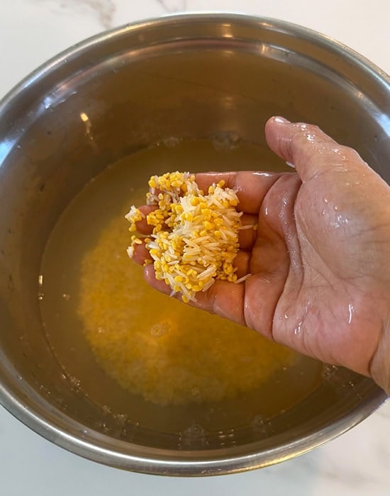 hand showing rice dal soaked in bowl