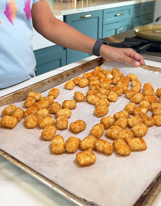 baked tater tots arranged on a baking sheet lined with parchment paper