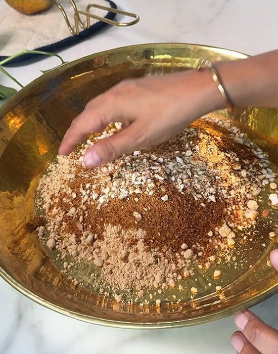 hand touching all ladoo ingredients added to a plate