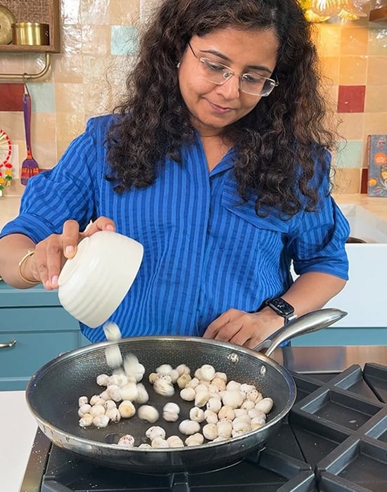 woman adding bowl of makhana to pan