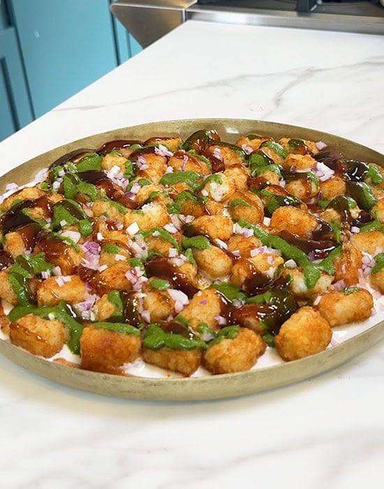 tater tots drizzled with green and sweet chutneys